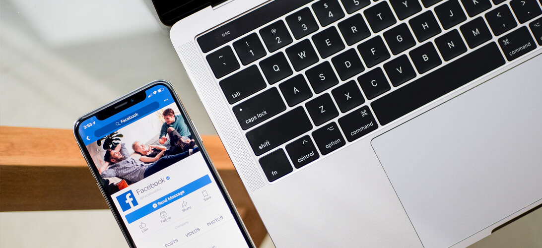 Celular com aplicativo do facebook ao lado de computador